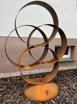 Abstrakte, dreidimensionale Skulptur aus kreisförmig geschwungenen Stahlbändern mit markanter Rostpatina auf rundem Standfuß.